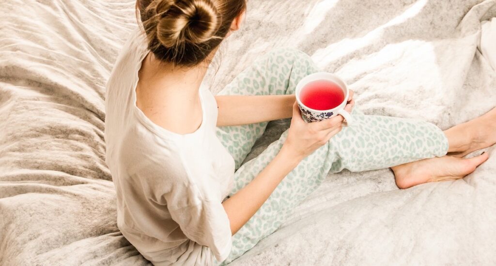 ベッドの上でお茶を飲みながら休憩している女性